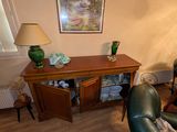 un salon avec un canapé, un fauteuil, une table, une lampe et des tableaux accrochés au mur