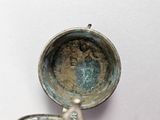 a silver cup with a handle on a white surface