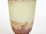 a glass vase with a brown base on a white surface