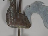 a metal rooster on a pole on the wall