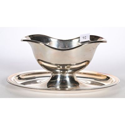 une assiette en argent posée sur une soucoupe, le tout sur un plateau