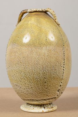 un vase jaune muni d'une anse, posé sur une table en bois