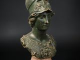 un buste en bronze représentant une femme portant un casque, posé sur un socle en bois