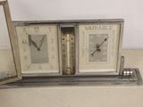 two clocks sitting on top of a table with a picture frame