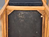 an old wooden chair with a black cushion on top of it