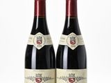 deux bouteilles de vin rouge posées l'une à côté de l'autre sur une surface blanche