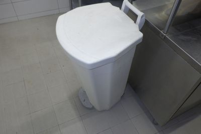 des toilettes blanches situées dans une salle de bains, à côté d'une poubelle