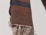 two pieces of brown and blue woven fabric on a white surface
