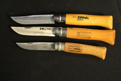 three knives are lined up on a black surface with a wooden handle
