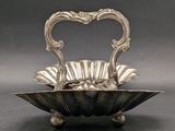 an antique silver plate with a heart shaped handle on a stand