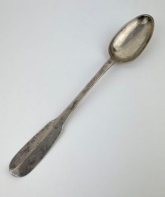 une cuillère en argent posée sur une surface blanche, avec une petite cuillère au milieu