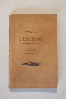 un vieux livre posé sur une table à côté d'un mur blanc