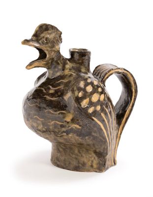 a brown vase with a bird on it on a white surface