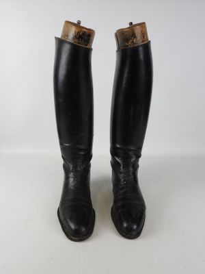 pair of black leather riding boots on white surface with white background