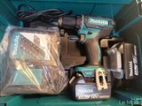 a cordless drill and two batteries in a green box