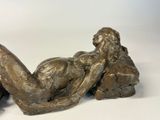 a bronze statue of a woman laying on her stomach