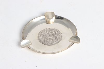 a silver ashtray with a silver medallion on it