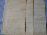 two pages of old paper with writing on them sitting on a table