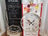 une horloge posée sur un pied à côté d'un tableau noir