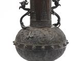 un vase en bronze surmonté de deux oiseaux