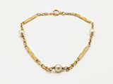 a close up of a gold bracelet with pearls on a white background