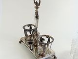 a silver tea set on a silver tray with a glass