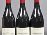 three bottles of red wine are lined up on a table