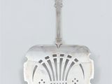 an old silver spoon with a design on it on a white surface