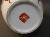 a close up of a white vase with a red design on it