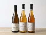trois bouteilles de vin sont alignées sur une table en bois