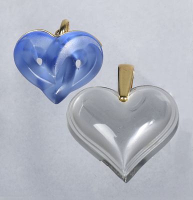 two heart shaped glass pendants with gold accents on a white background