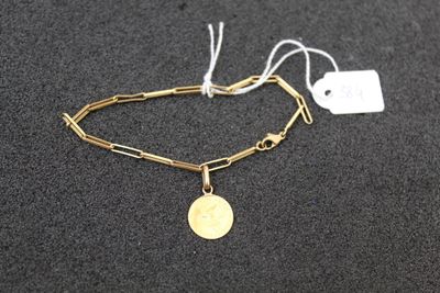 a gold chain bracelet with a coin on top of it