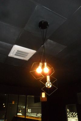 un plafond noir d'où pendent deux ampoules