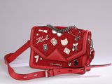 someone is holding a red purse with a bunch of charms on it