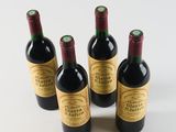 four bottles of wine are lined up in a row on a white surface