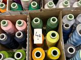 many spools of thread in boxes on a table