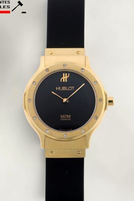 gros plan d'une montre sur une surface blanche avec un bracelet noir