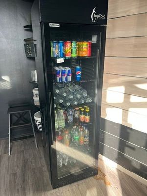 un réfrigérateur contenant des boissons et des sodas, situé dans une pièce