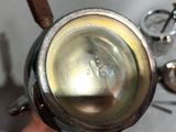 a person holding a silver tea pot with a wooden handle