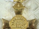 gold medal with a red ribbon and a crown on top of a white blanket