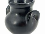 a black vase that is sitting on a white surface