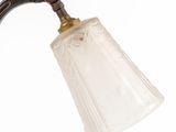 an antique brass and frosted glass wall light with a glass shade