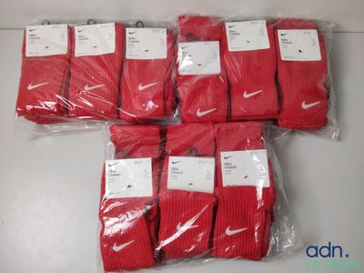 un tas de chaussettes Nike rouges dans des sacs en plastique posés sur une table