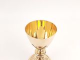 a gold cup that is sitting on a white table
