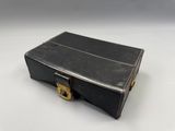 une vieille valise noire posée sur une surface blanche