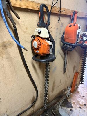 une photo d'une tronçonneuse et d'autres outils accrochés au mur