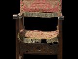 an old wooden chair with a red and gold upholstered seat