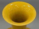 a yellow vase sitting on a table with a gray background