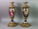 pair of antique vases with painted images on them sitting on a table