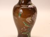 a brown vase with flowers on it sitting on a table